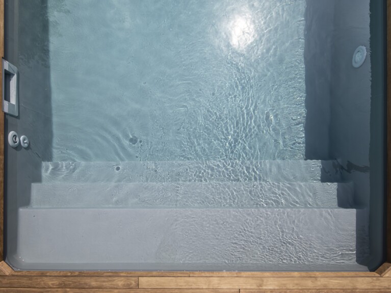 Ansicht eines Pools von oben. Zusehen sind Treppen, Düsen und ein Holzrahmen.