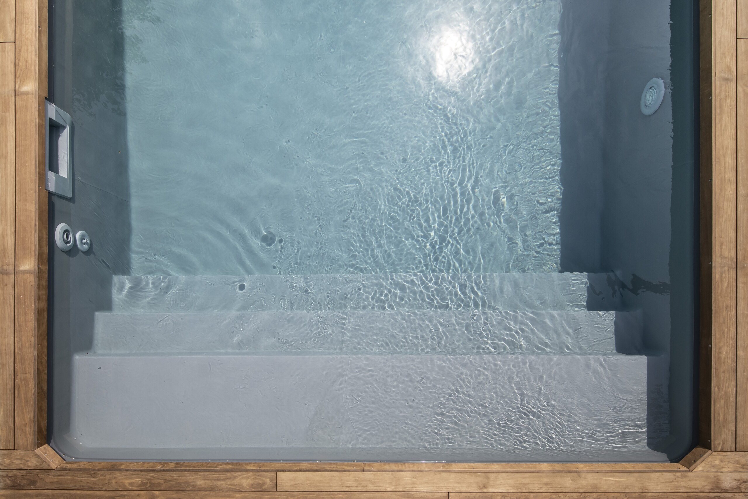 Ansicht eines Pools von oben. Zusehen sind Treppen, Düsen und ein Holzrahmen.